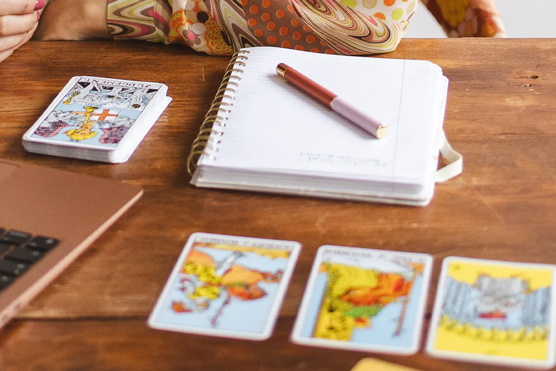 Cartes de tarot posées avec un carnet et un stylo sur un bureau