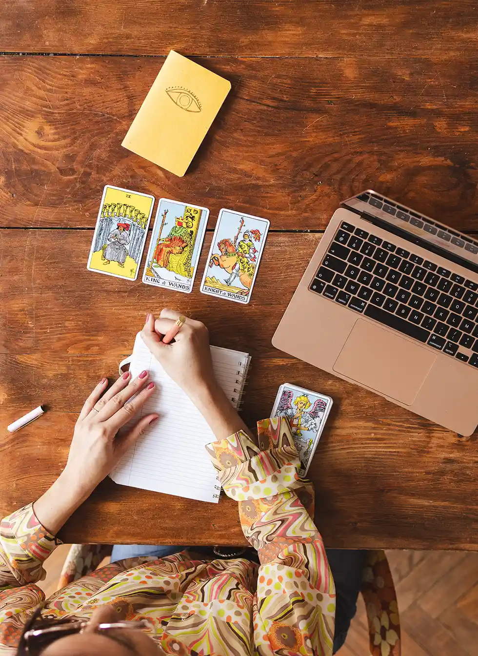 Vue de dessus du bureau avec un carnet, un tirage de tarot et un ordinateur