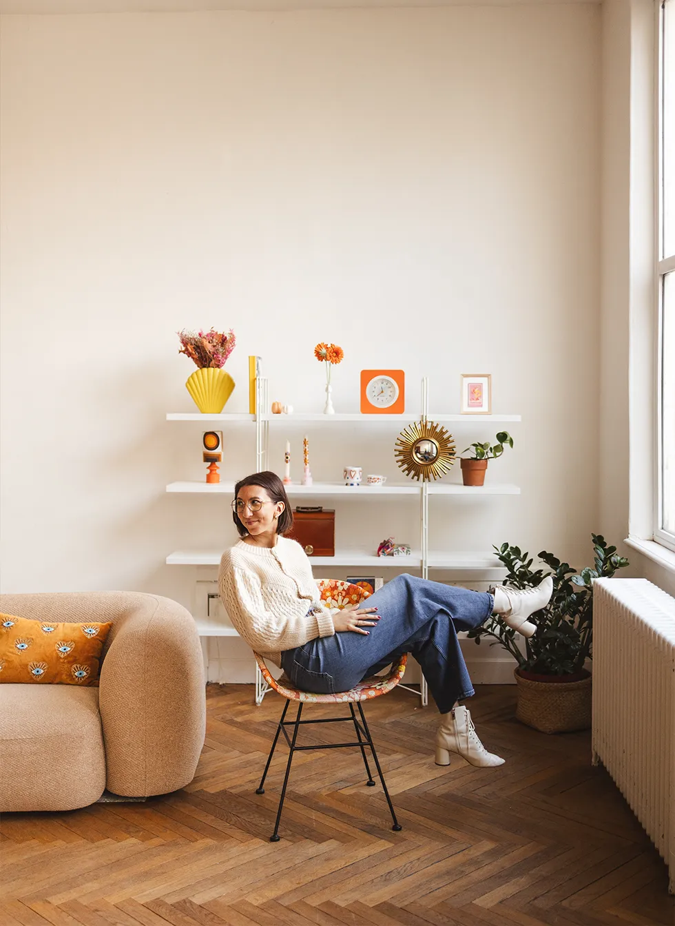 Marjorie assise sur une chaise rétro dans son cabinet, regardant sur le côté avec un sourire